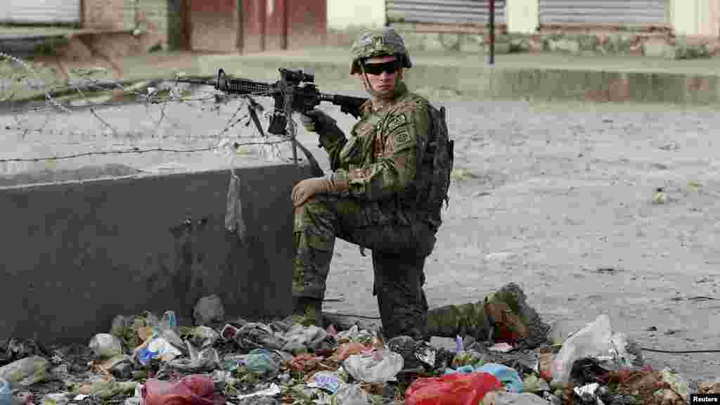 A U.S. soldier keeps watch at the site where a suicide car bomber rammed a foreign convoy along a major road out of Afghanistan's capital, Kabul, Oct. 13, 2014. 