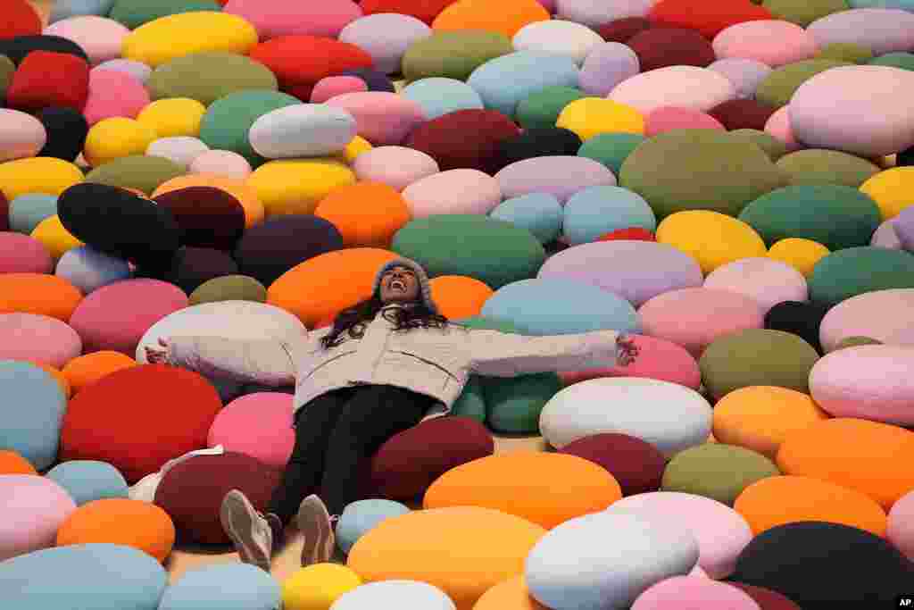 A woman lies on the colorful art display cushions showcased at a luxury shopping mall in Beijing.