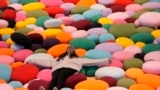 A woman lies on the colorful art display cushions showcasing at a luxury shopping mall in Beijing, Dec. 3, 2024.