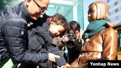 30일 아버지와 함께 부산 일본영사관 후문 앞을 방문한 어린이가 '평화의 소녀상'을 만지고 있다. 지난 28일 이곳에 처음 설치됐던 소녀상은 동구청의 강제 철거로 압수된 지 이틀만인 이날 다시 설치됐다. 