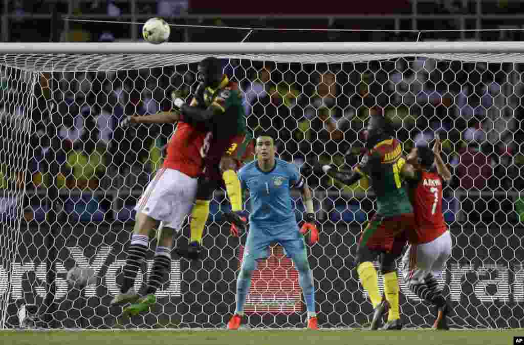 Egypt goalkeeper Essam El Hadary, center, watches as Cameroon's Nicolas Nkoulou, 2nd left, jumps to score his side's first goal during the African Cup of Nations final soccer match between Egypt and Cameroon at the Stade de l'Amitie, in Libreville, Gabon,