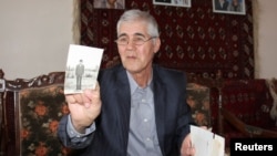 Muhammad Bekjanov, 63, a newspaper editor who was jailed for 18 years, shows a photo of himself taken at a younger age, after being released in February at his home in Yangibazar, Uzbekistan, March 1, 2017. 