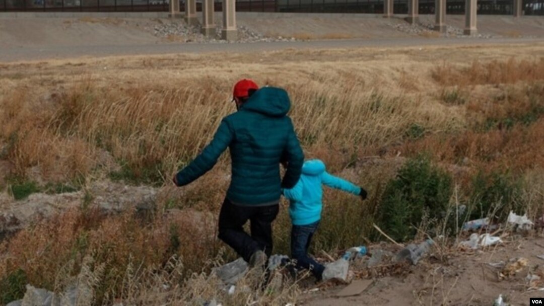 Un migrante guatemalteco y su hijo cruzan la frontera natural de Río Grande entre El Paso, estado de Texas, Estados Unidos, y Ciudad Juárez, estado de Chihuahua, México, en busca de asilo político el 26 de enero de 2021.