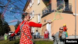 Circus clown Tanja Selmer performs for seniors at their retirement home, as the spread of the coronavirus disease (COVID-19) continues in Jueterbog, south of Berlin, Germany, April 7, 2020. (REUTERS/Fabrizio Bensch)