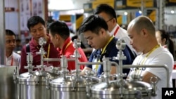 Attendees inspect brewing equipment at the 2018 Craft Beer of China Exhibition in Shanghai, May 16, 2018.