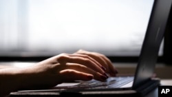 Seorang perempuan sedang mengetik di laptop. Pandemi ternyata membuat praktik menggunakan joki dalam tugas sekolah marak. (Foto: AP)
