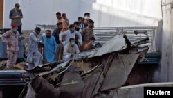 Warga berkerumun di dekat kepingan pesawat yang jatuh di kawasan hunian dekat bandara di Karachi, Pakistan, 22 Mei 2020. (Foto: dok).