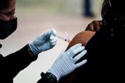 FILE – A member of the Philadelphia Fire Department administers a COVID-19 vaccine, March 26, 2021.