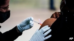 FILE – A member of the Philadelphia Fire Department administers a COVID-19 vaccine, March 26, 2021. 