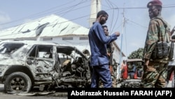 Para petugas memeriksa puing-puing di lokasi pengeboman bunuh diri di dekat pos pemeriksaan keamanan di Mogadishu, 13 Februari 2021. (Foto: AFP)