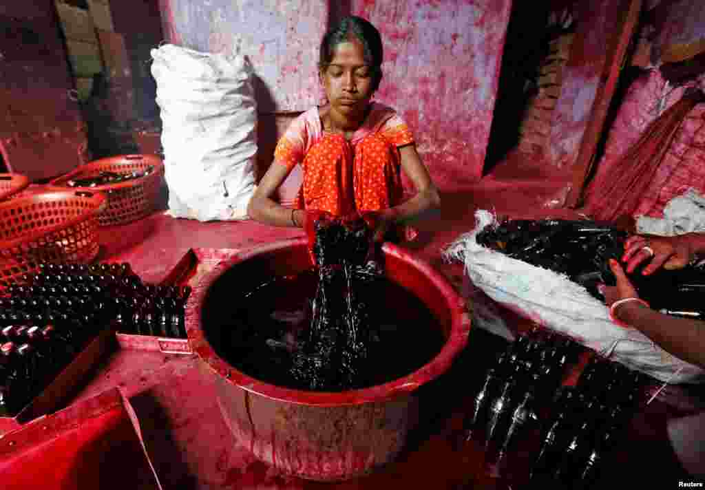 A worker fills bottles with Alta, a red dye which Hindu women apply with cotton on the border of their feet during marriages and religious festivals, at a workshop in Kolkata, India.