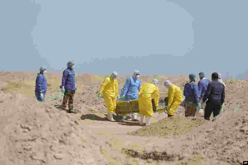 Los trabajadores del Ministerio de Salud iraquí llevan un ataúd a un nuevo cementerio para las personas que murieron de COVID-19, en las afueras de la ciudad de Najaf, Iraq.&nbsp;