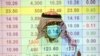 A Saudi trader wears a mask as he monitors stock information at the Saudi stock market in Riyadh, Saudi Arabia.