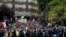 A man in a crowd holds a poster on which is written, "Our liberties pass away," during a protest against the COVID vaccine and vaccine passports, in Paris, Aug. 7, 2021. 
