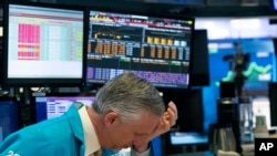 A trader holds his hand to his head after trading was halted for the day at the New York Stock Exchange, March 18, 2020, in New York. Remove