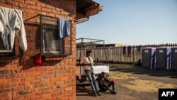 Two men rest outside the Tsolo Community Hall in Johannesburg's Katlehong township, Sept. 9, 2019, where around 250 people, are hosted after being displaced by anti-foreigner violence that hit South Africa's financial capital.