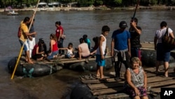 FILE - Rafts loaded with passengers leave Tecun Uman, Guatemala, to cross the Suchiate River to reach Mexico, June 25, 2019. 