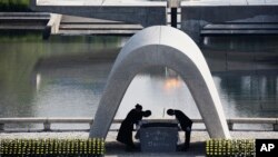 FILE - Kazumi Matsui, right, mayor of Hiroshima, and the family of the deceased bow, Aug. 6, 2015, at the Hiroshima Memorial Cenotaph during the ceremony to mark the 70th anniversary of the bombing at the Hiroshima Peace Memorial Park in Hiroshima, Japan. 