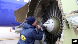A National Transportation Safety Board investigator examines damage to the engine of the Southwest Airlines plane that made an emergency landing at Philadelphia International Airport in Philadelphia, April 17, 2018.