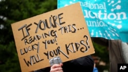 A sign is held up by a striking teacher at a demonstration in Manchester, England, Feb. 1, 2023.