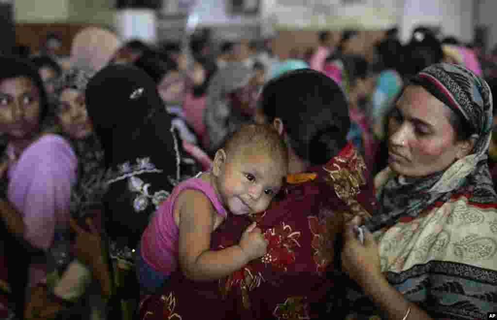 A Bangladeshi Muslim woman carrying a child stands in a queue to buy train tickets to return home before the Eid al-Adha holiday, at Kamlapur central train station in Dhaka, Bangladesh, Sept. 19, 2015.