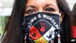 FILE - Jeannie Hovland, the deputy assistant secretary for Native American Affairs for the U.S. Department of Health and Human Services, poses with a Missing and Murdered Indigenous Women mask, in Anchorage.