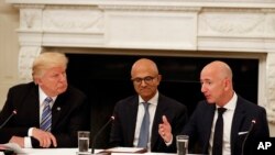 FILE - President Donald Trump, left, and Satya Nadella, Chief Executive Officer of Microsoft, center, listen as Jeff Bezos, Chief Executive Officer of Amazon, speaks during an American Technology Council roundtable in the State Dinning Room of the WH.