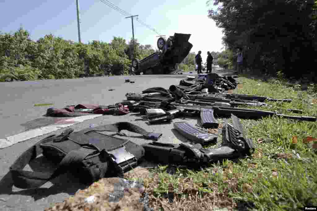 Gear and weapons of victims are placed by the road as security forces inspect the site of a bomb attack on police in the troubled southern Thai province of Narathiwat, March 30, 2014.