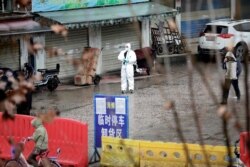 FILE - A worker in a protective suit is seen at the closed seafood market in Wuhan, Hubei province, China, Jan. 10, 2020.