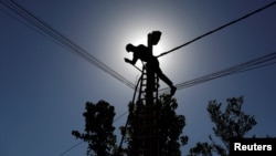 FILE - An Iraqi technician works on an electricity pole damaged during fighting between Iraqi forces and Islamic state fighters, in eastern Mosul, Iraq, April 26, 2017. 