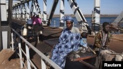 People on donkey-drawn carts cross a strategic bridge over a dam on the Niger River secured by French forces in Markala, Mali, January 18, 2013.