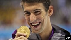 United States' Michael Phelps displays his gold medal for the men's 100-meter butterfly swimming final at the Aquatics Centre in the Olympic Park during the 2012 Summer Olympics in London, Friday, Aug. 3, 2012. (AP Photo/Matt Slocum)