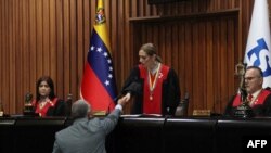 Handout picture released by the Venezuelan Electoral Council (CNE) shows the President of the CNE Elvis Amoroso shaking hands with Venezuelan Supreme Court of Justice (TSJ) President Caryslia Rodriguez in Caracas on August 5, 2024.