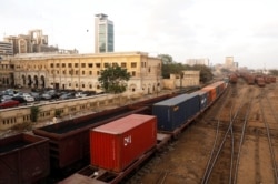 FILE - Cargo trains carrying shipping containers and coal dust cross under a bridge with the backdrop of City Station, built in the British Raj era, in Karachi, Pakistan, Sept. 24, 2018.