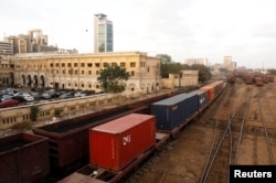 FILE - Cargo trains carrying shipping containers and coal dust cross under a bridge with the backdrop of City Station, built in the British Raj era, in Karachi, Pakistan, Sept. 24, 2018.