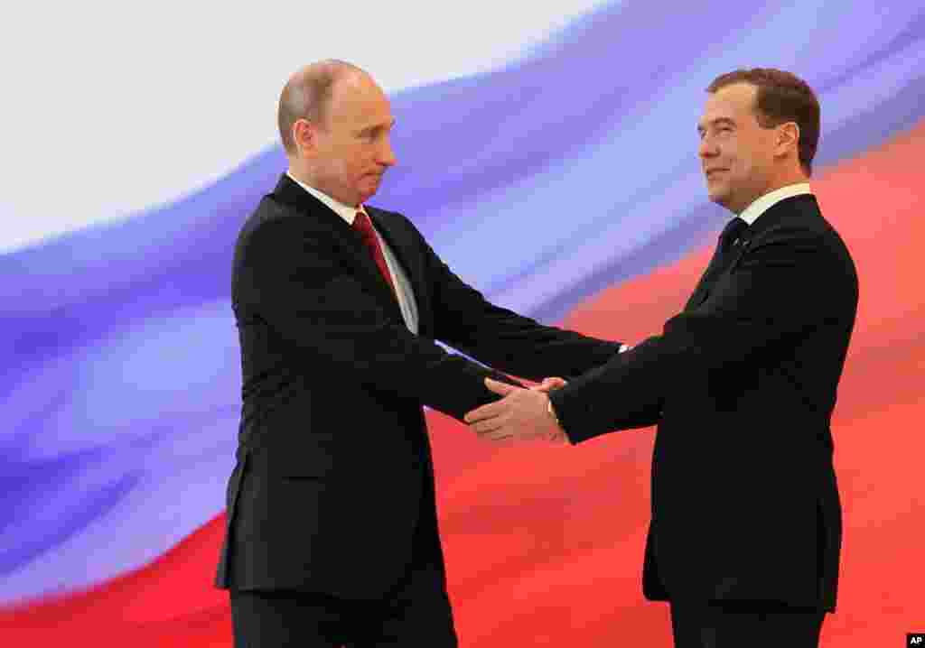 Presiden Rusia Vladimir Putin (kiri) dan mantan Presiden Dmitry Medvedev berjabat tangan pada upacara pelantikan.