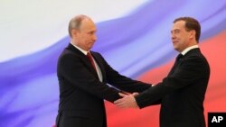 Russian President Vladimir Putin, left, and former President Dmitry Medvedev shakes hands at the inauguration ceremony. 