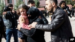 A Turkish man helps a Syrian woman carrying a wounded Syrian girl to a hospital in Kilis, Turkey, Feb. 15, 2016.