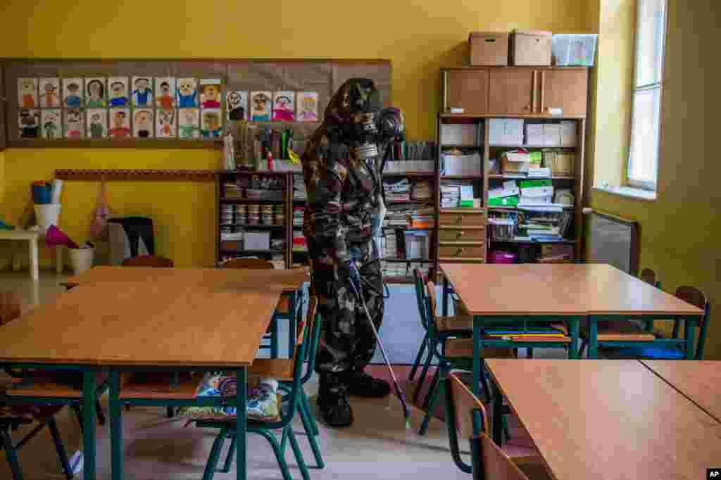 یک سرباز در لباس کار در حال ضدعفونی کردن کلاس‌های مهد کودک و مدرسه ابتدایی برای پیشگیری از گسترش ویروس جدید کرون. در بوداپست، مجارستان.