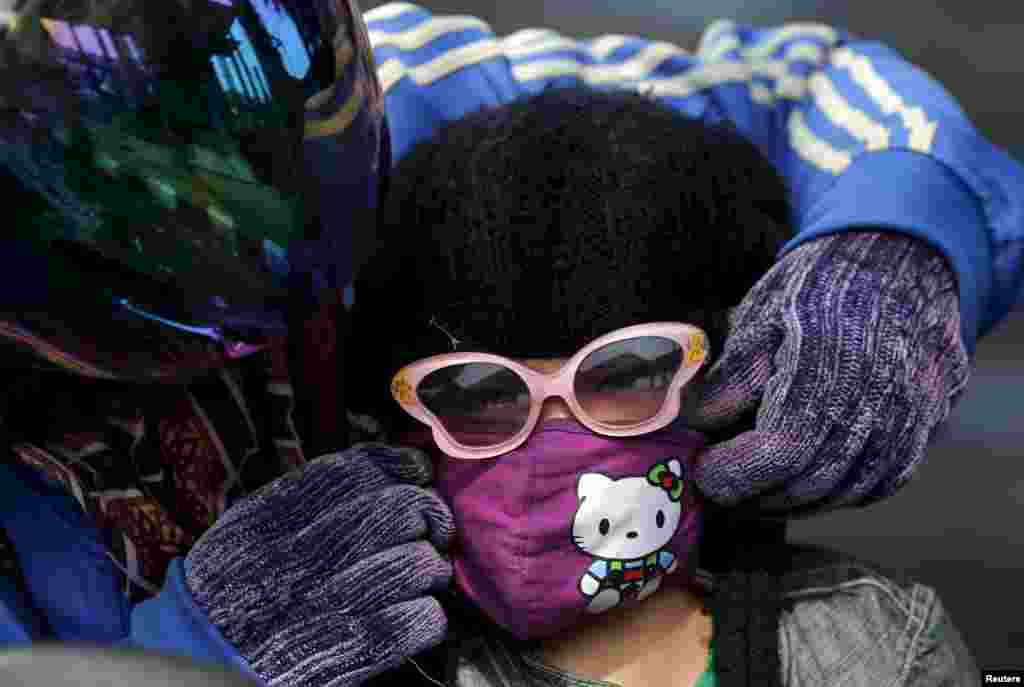 A mother adjusts her daughter&#39;s mask as they head home from school in Kertapati district in Palembang, on the Indonesian island of Sumatra. The worsening haze across northern Indonesia, neighboring Singapore and parts of Malaysia forced some schools to close and airlines to delay flights this week, while Indonesia ordered a crackdown on lighting fires to clear forested land.