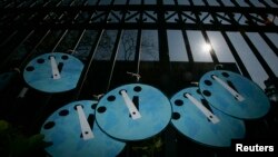 FILE - Greenpeace activists put up mock "doomsday clocks" which symbolize their "Time's Up, Save the Climate" warning, during a protest. Climate change “will likely pose significant national security challenges” over the next 20 years, a U.S. government report says.