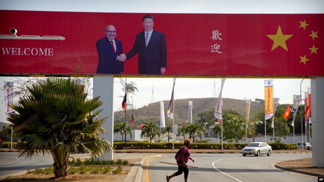 A woman crosses the street near a billboard commemorating the state visit of Chinese President Xi Jinping in Port Moresby, Papua New Guinea, Nov. 15, 2018.