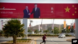 A woman crosses the street near a billboard commemorating the state visit of Chinese President Xi Jinping in Port Moresby, Papua New Guinea, Nov. 15, 2018.