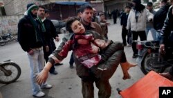 In this March 11, 2012 photo, a man carries a boy who was severely wounded during heavy fighting between Syrian rebels and Syrian Army forces in Idlib, north Syria. 