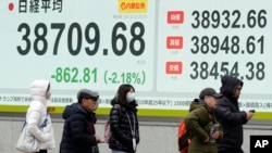 People walk in front of an electronic stock board showing Japan's Nikkei index at a securities firm, Feb. 3, 2025, in Tokyo.