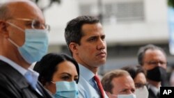 Flanqueado por miembros del partido, el líder de la oposición venezolana Juan Guaidó, en el centro, durante una conferencia de prensa, un día después de las elecciones parlamentarias, en Caracas, Venezuela. Diciembre 2, 2020.