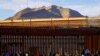 2023年1月5日，移民越过里约布拉沃河后，在美墨边境围栏附近排队申请庇护。（路透社照片）