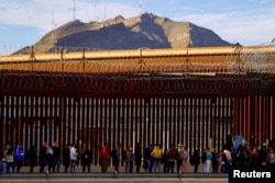 FILE - Migrants queue near the border fence, after crossing the Rio Bravo river, to request asylum in El Paso, Texas, U.S., as seen from Ciudad Juarez, Mexico January 5, 2023. (REUTERS/Jose Luis Gonzalez/File Photo)