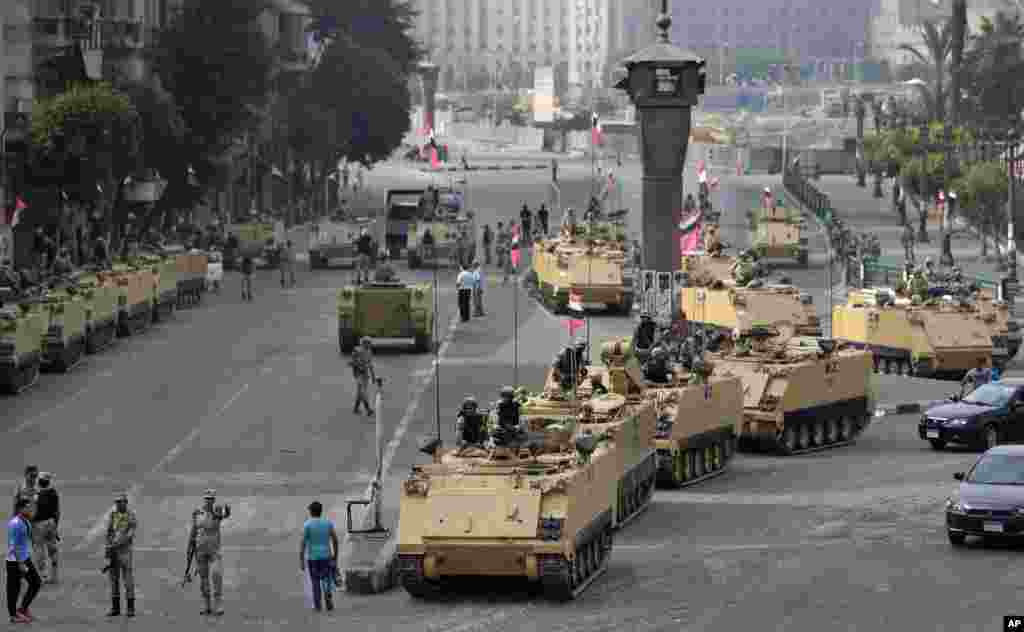 Egyptian army soldiers take their positions on top and next to their armored vehicles while guarding an entrance to Tahrir square, in Cairo.