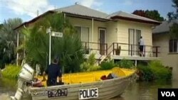 Seorang polisi Australia menggunakan perahu kecil untuk memeriksa kawasan yang terkena banjir.